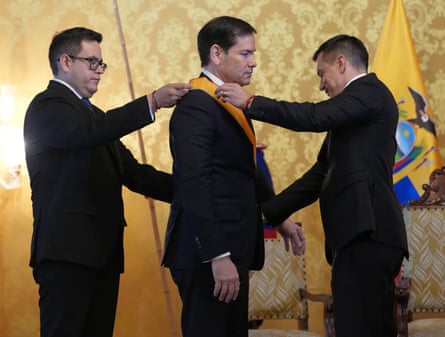 Two men put a metal on a third man in the center